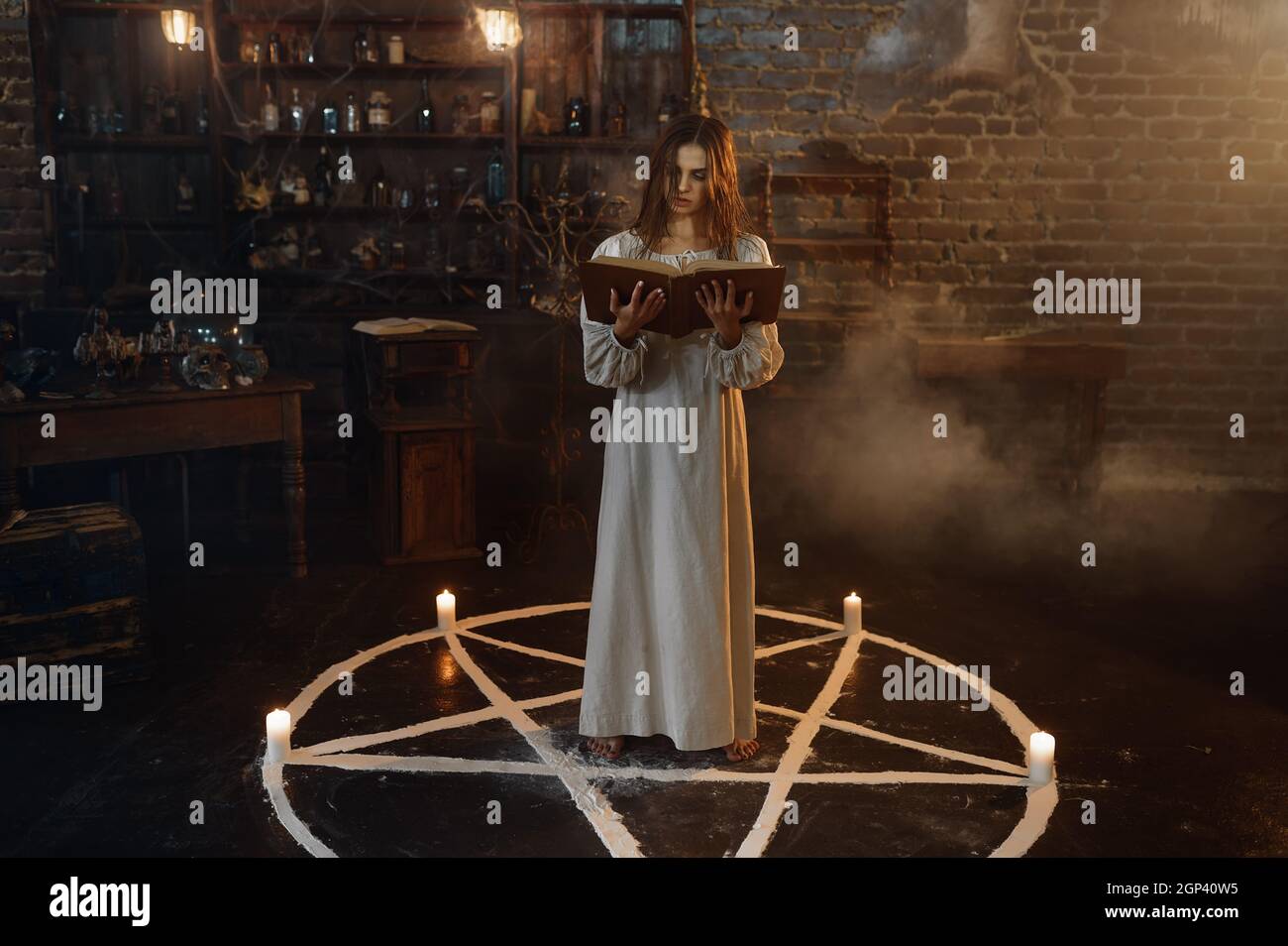 Donna demoniaca con libro di incantesimi in piedi nel cerchio magico, i demoni gettano fuori. Esorcismo, mistero paranormale rituale, religione oscura, orrore notturno, Foto Stock
