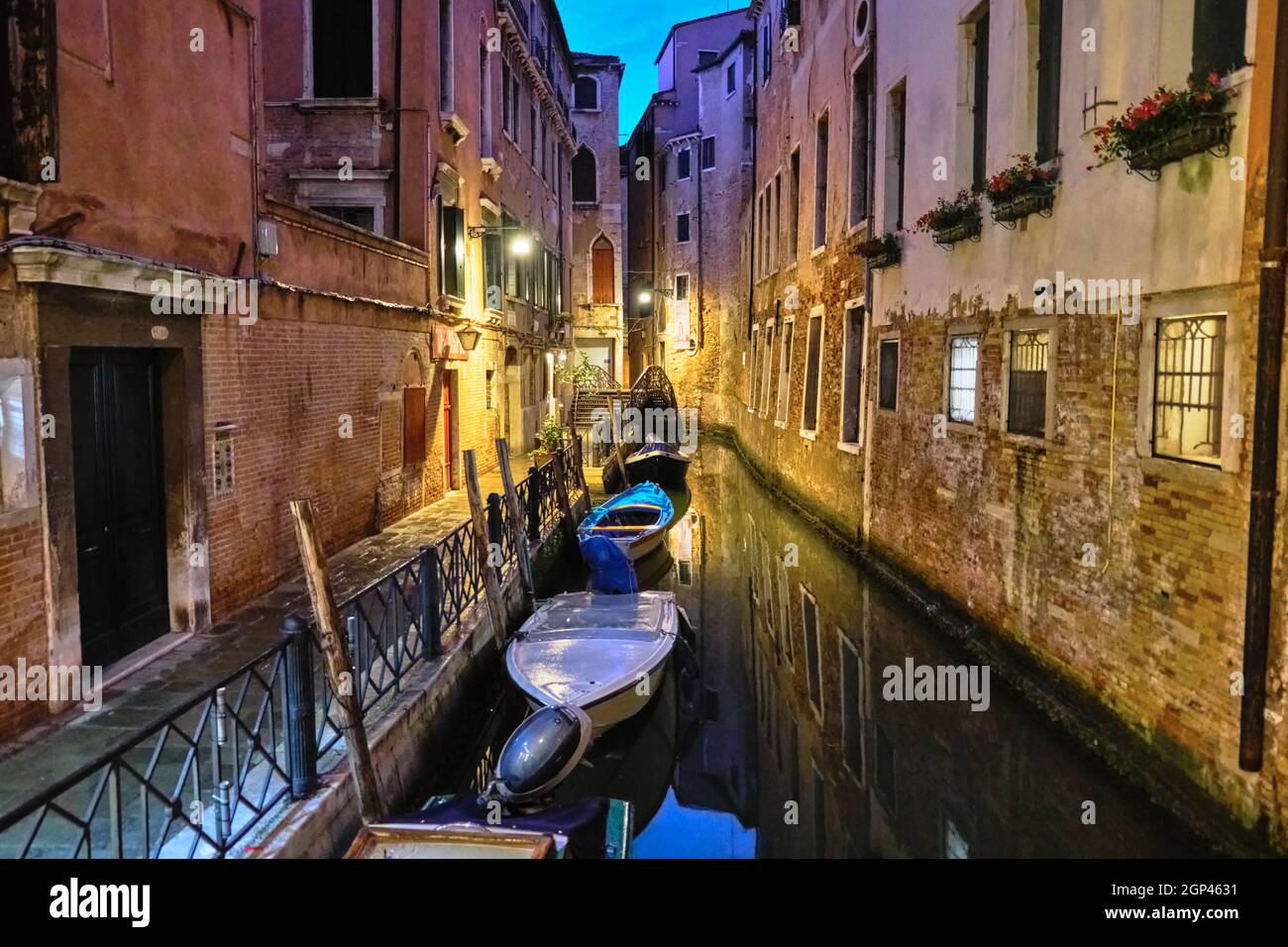 Vista notturna su uno stretto canale e barche parcheggiate di notte a Venezia, Italia Foto Stock