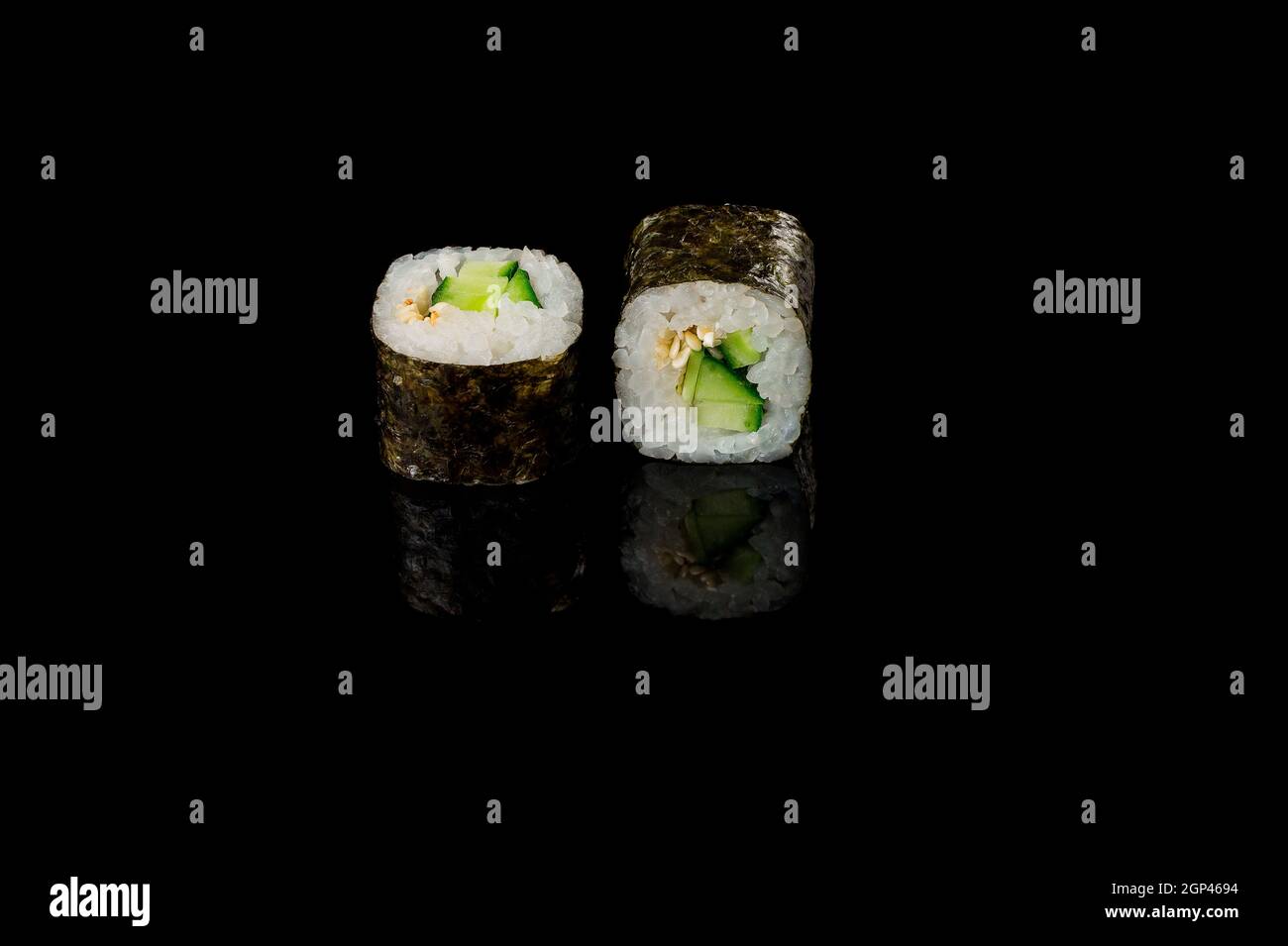 Panini neri con salmone e riso su sfondo nero con riflessi. Primo piano, vista dall'alto. Foto Stock