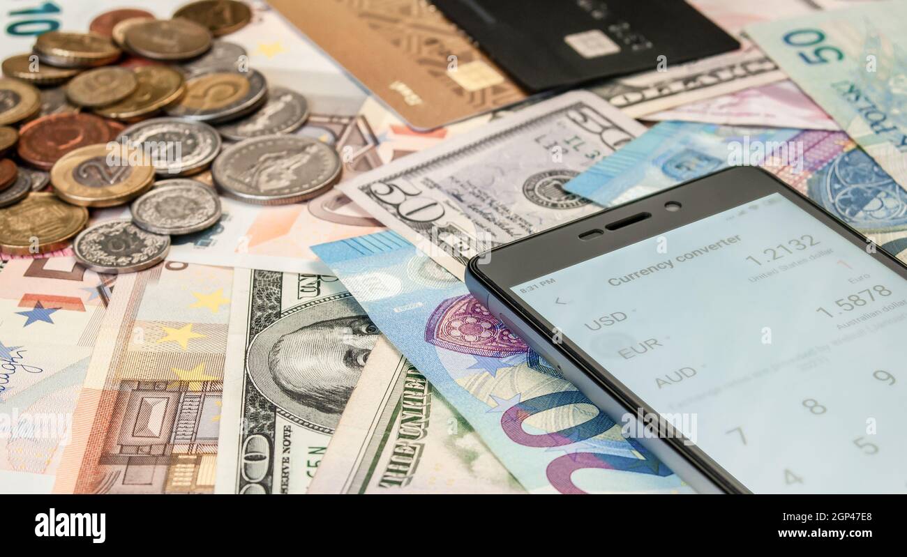 immagine ravvicinata di carte di credito, smartphone, monete e banconote di diverse valute Foto Stock