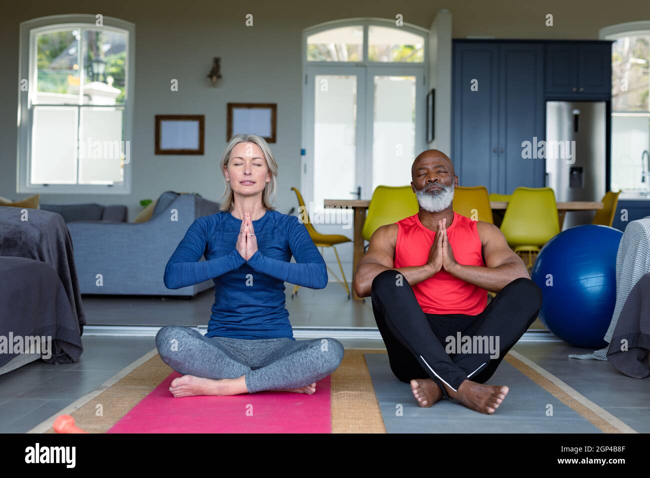 Coppia anziana felice in vestiti di esercitazione che praticano lo yoga insieme, meditating Foto Stock