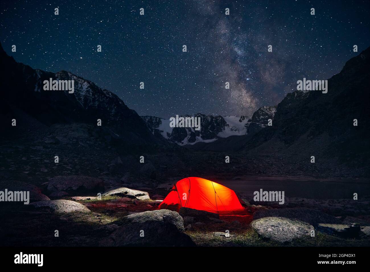 Tenda arancione con luce al campeggio nelle montagne sotto il cielo notturno con le stelle Foto Stock