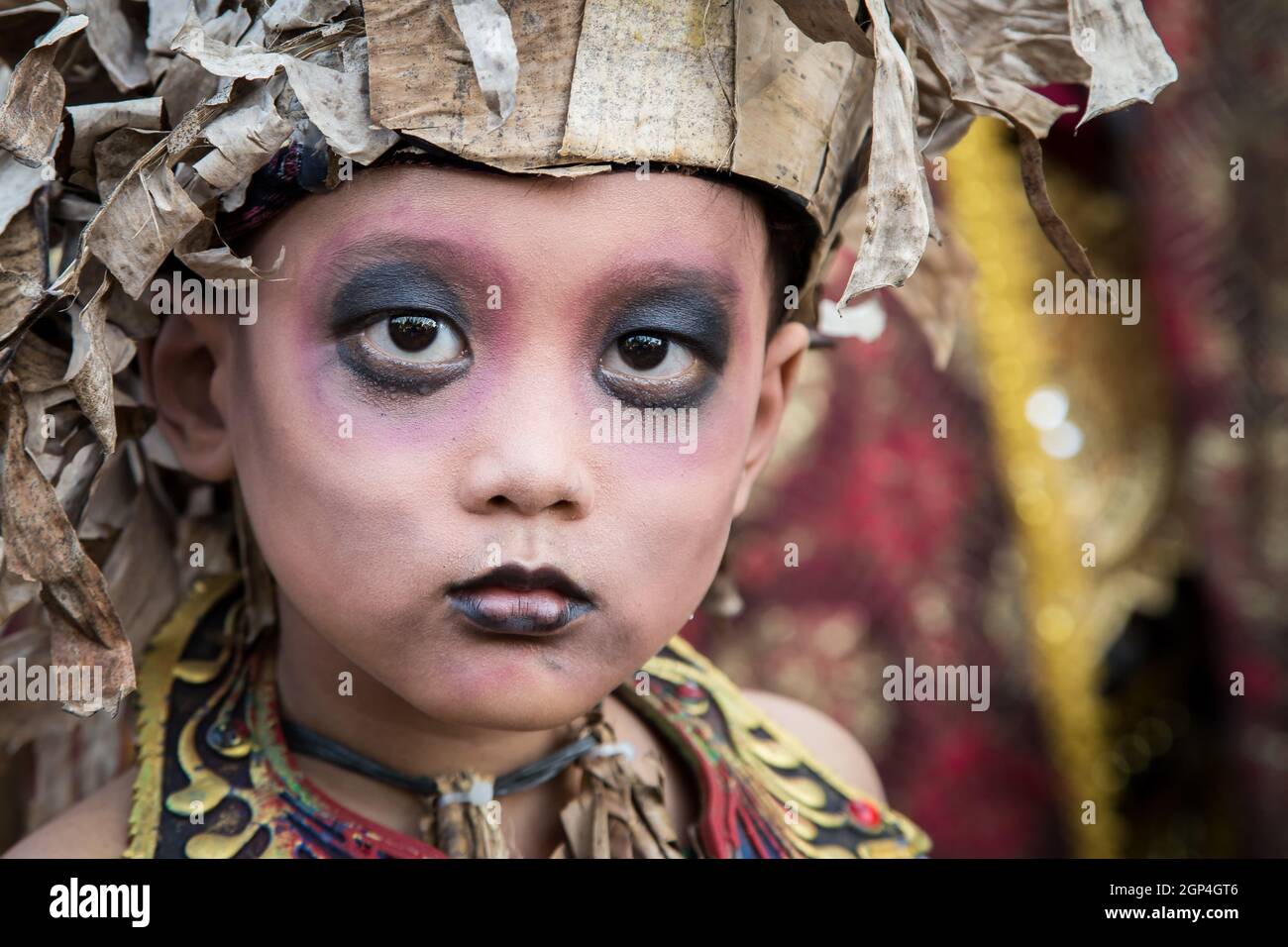 INDONESIA, BALI. RITRATTO DI UN BAMBINO CON UN OCCHIO INTENSO DURANTE IL BALI ART FESTIVAL Foto Stock