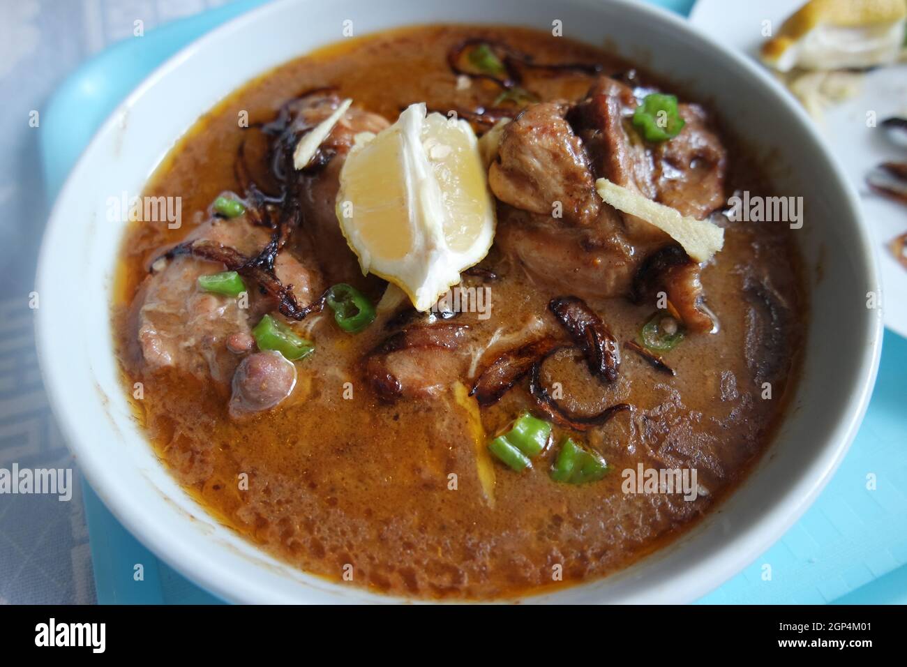 Primo piano del tradizionale piatto Haleem pakistano con insalata e succo di limone. Foto Stock