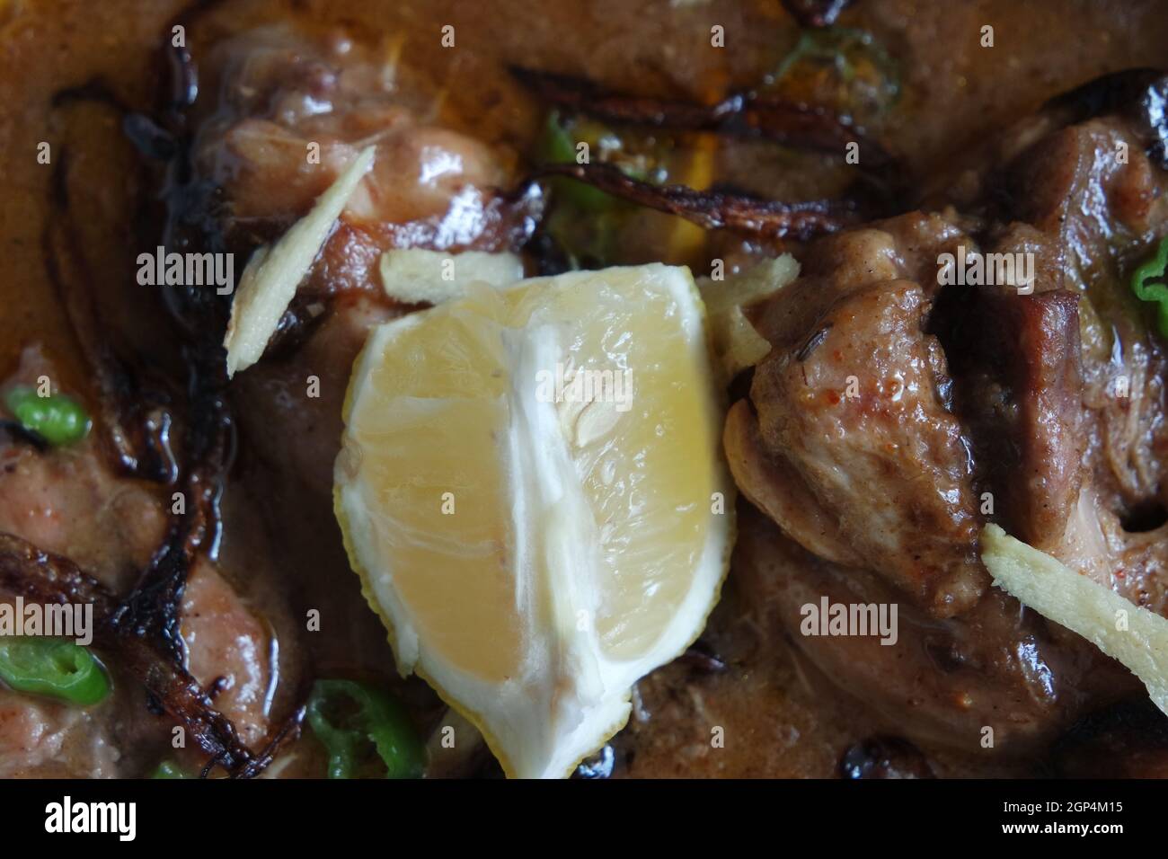 Primo piano del tradizionale piatto Haleem pakistano con insalata e succo di limone. Foto Stock