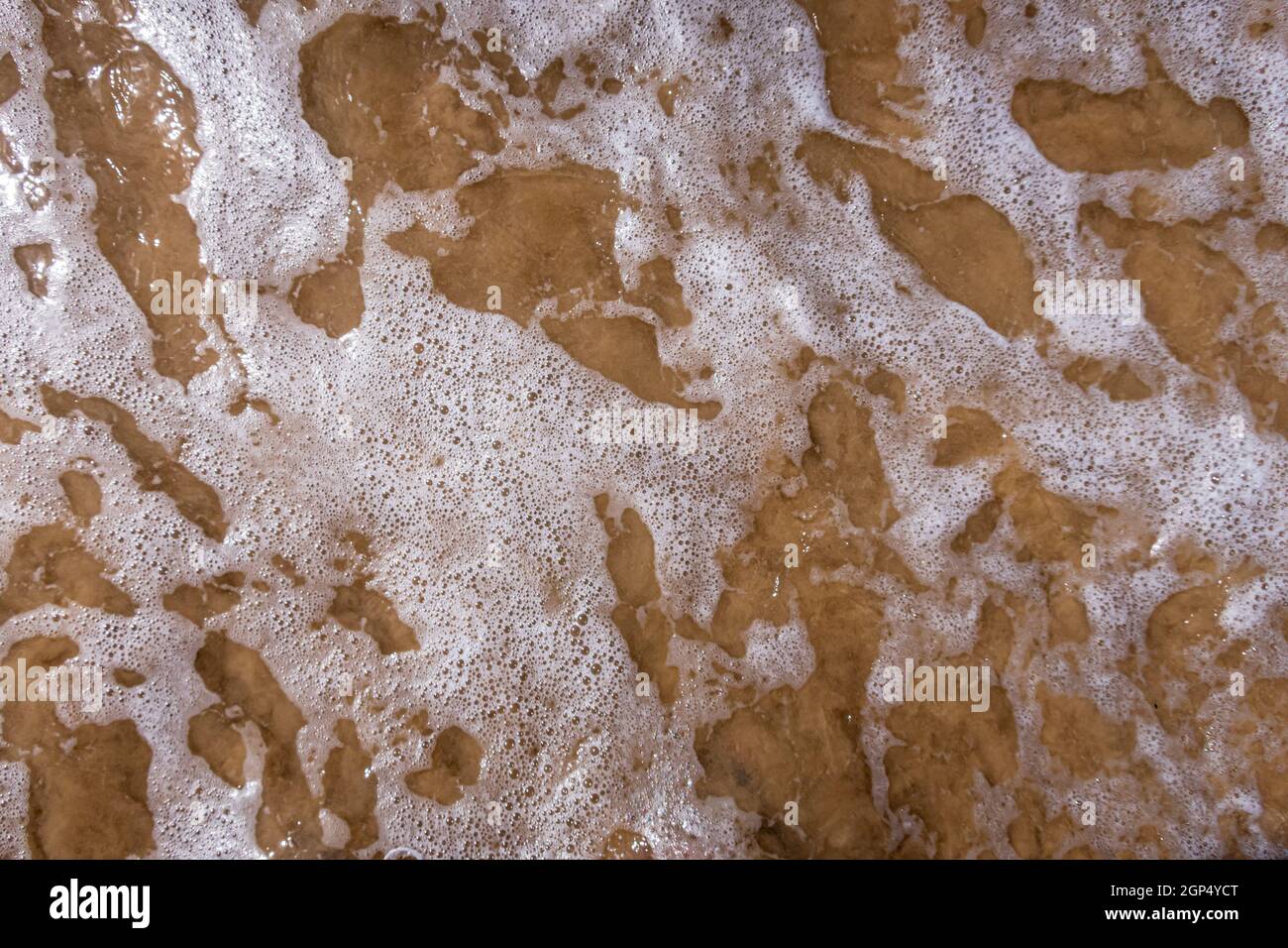 Lacy modello di onda e schiuma di mare che rotola sulla riva. Foto Stock