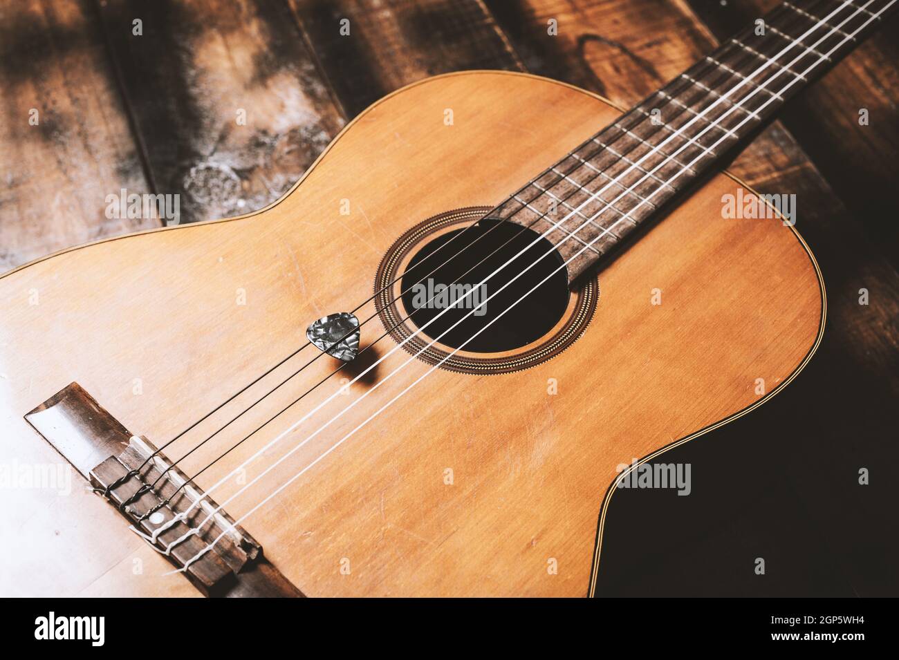 Primo piano chitarra pick su una vecchia chitarra classica. Un pick di  chitarra è un plectrum usato per le chitarre Foto stock - Alamy