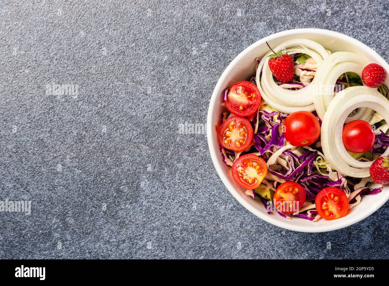 Vista dall'alto della ciotola per insalata colorata e sana con pomodori foglie fresche miste di verdure in un piatto su sfondo di pietra di cemento, salad snack Foto Stock