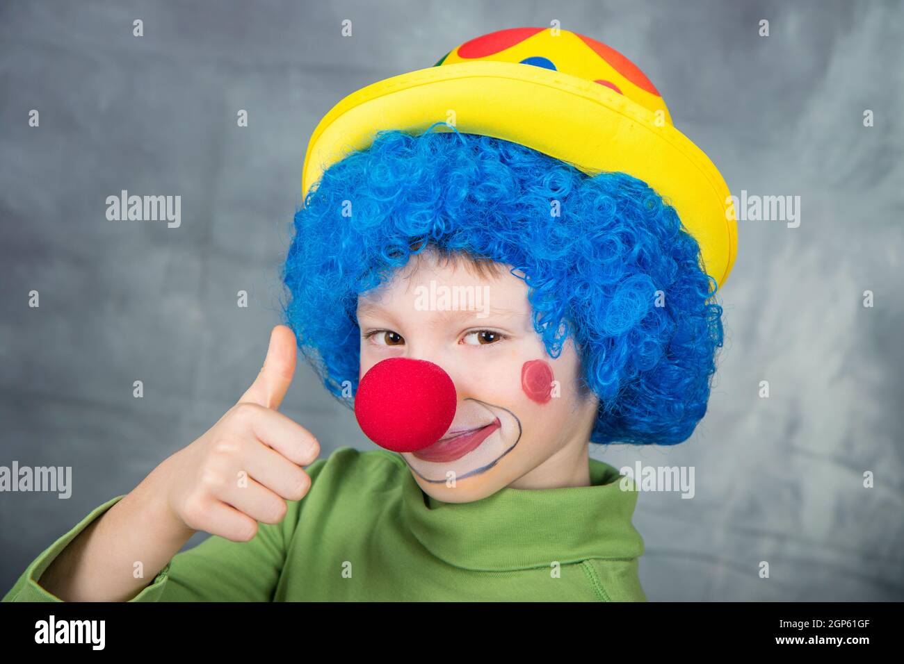 bambino vestito come un pagliaccio con la parrucca e il naso falso  sorridendo e pollici in su Foto stock - Alamy