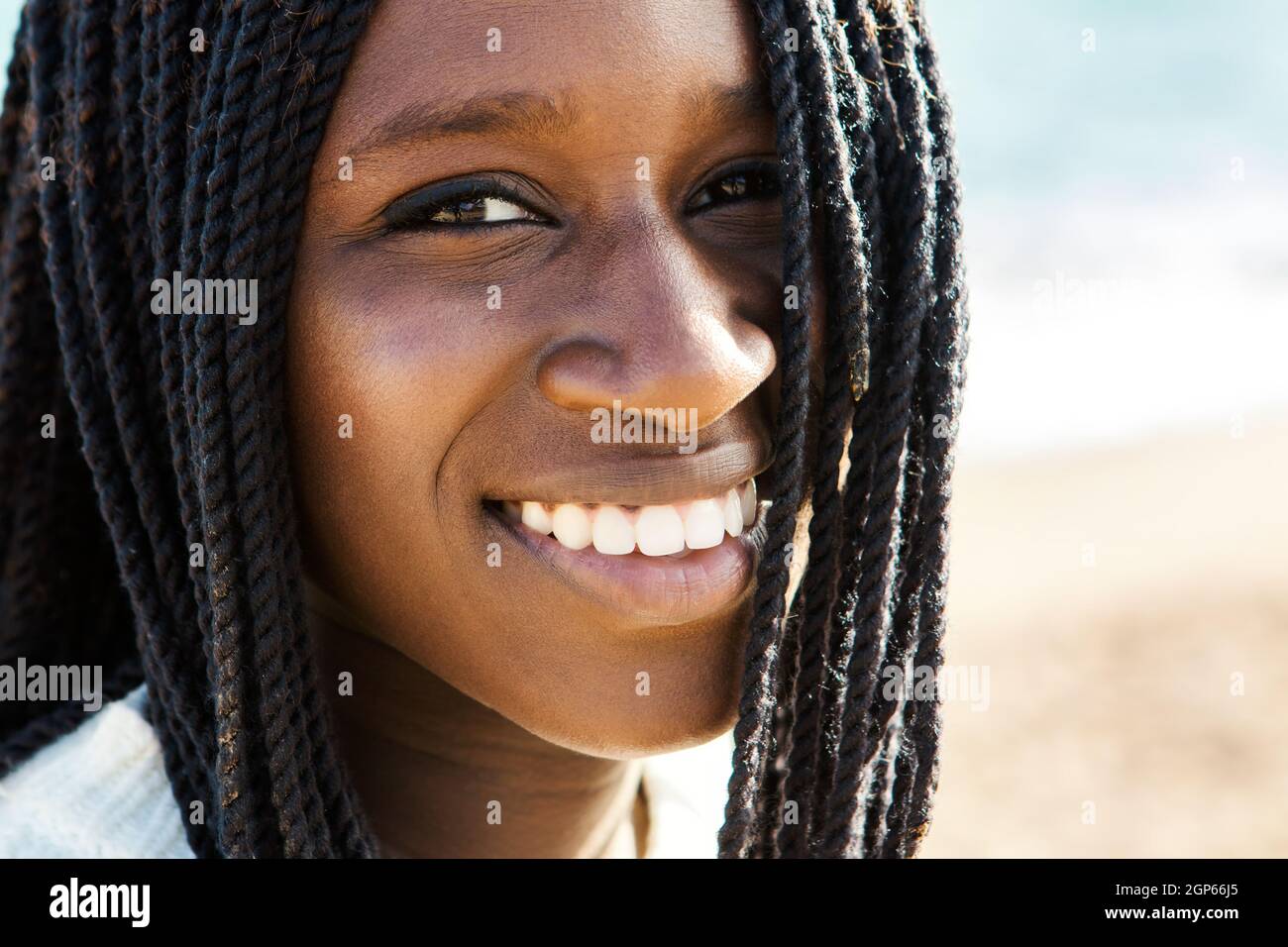 Primo piano su faccia esterna shot di esotico adolescente africano con braid.Girl sorridente e mostrando denti bianchi sani e perfetti. Foto Stock