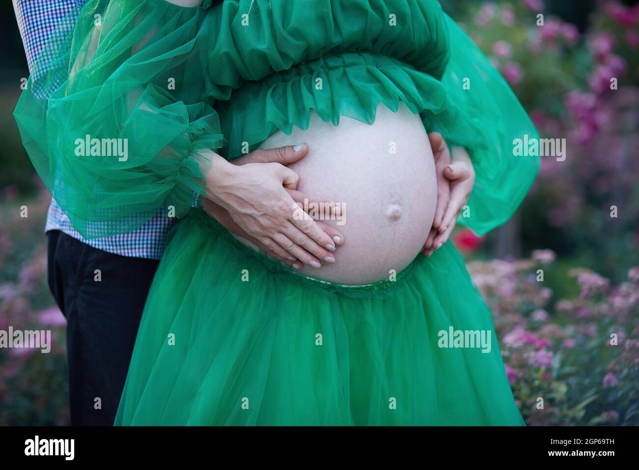 Gravidanza elegante. Tenerezza coppia incinta in giardino da vicino. Pancia grande. Foto di alta qualità Foto Stock