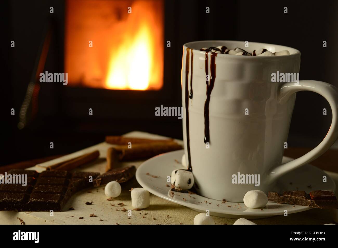 Una tazza di cioccolata calda che riposa di fronte ad un fuoco di stufa a legna. Foto Stock