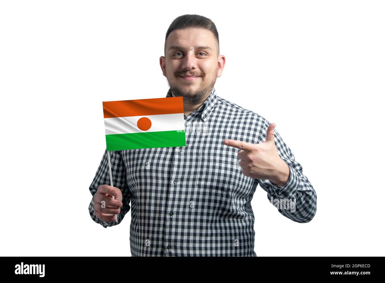 Ragazzo bianco che tiene una bandiera del Niger e punta il dito dell'altra mano alla bandiera isolata su uno sfondo bianco. Foto Stock