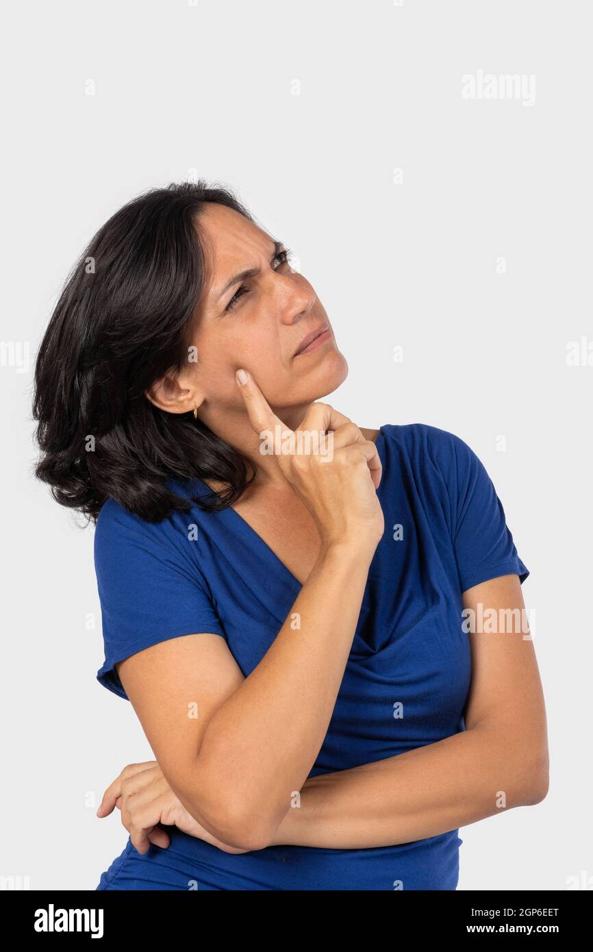 Una donna pensando,con un dito di una mano toccando il suo volto, indossa una camicia blu Foto Stock