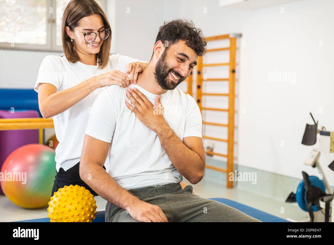 Donna fisioterapista che allunga il collo infortunato di un paziente maschio. Foto Stock
