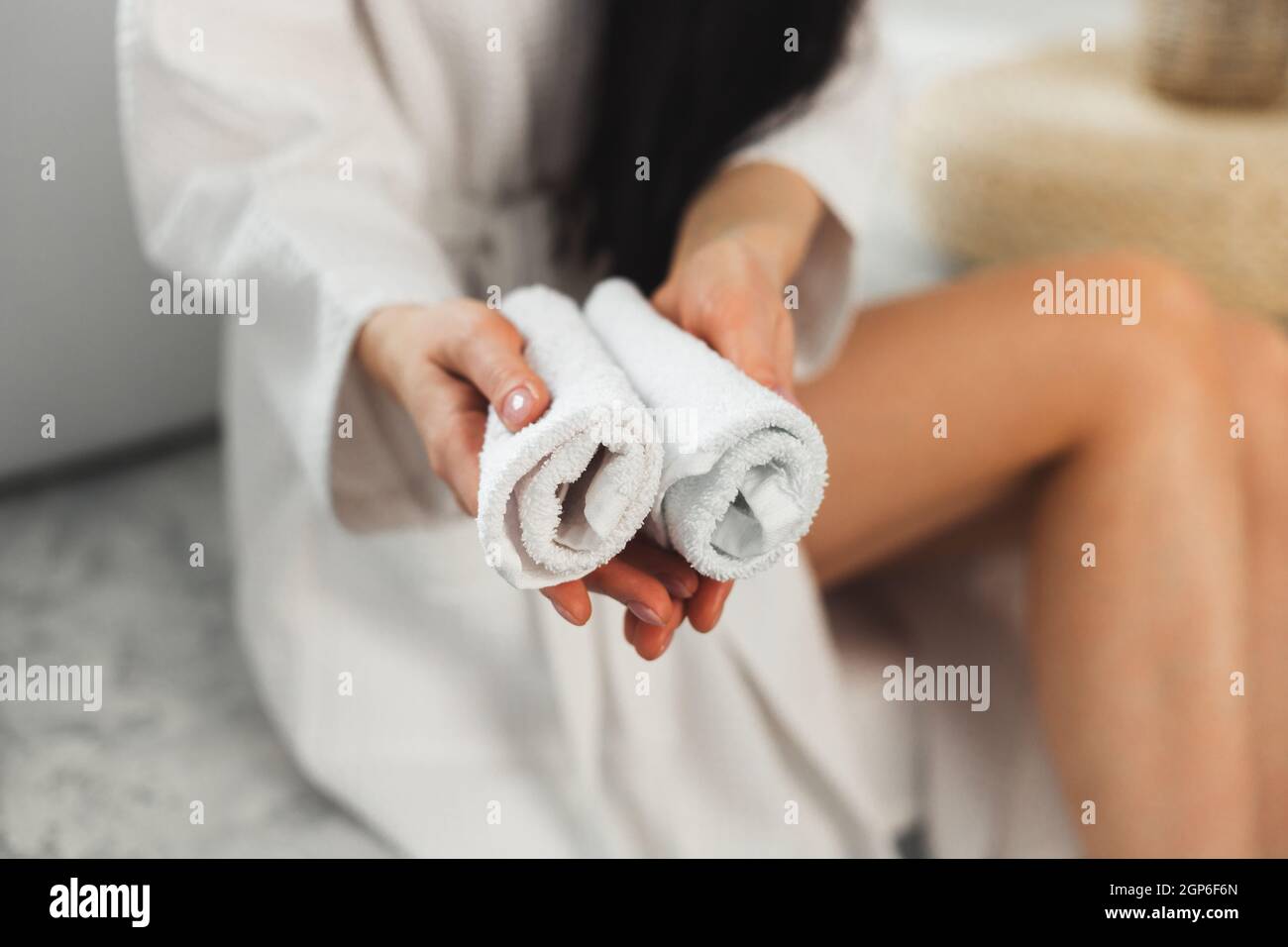 Donna che tiene puliti asciugamani bianchi arrotolati per le mani Foto Stock