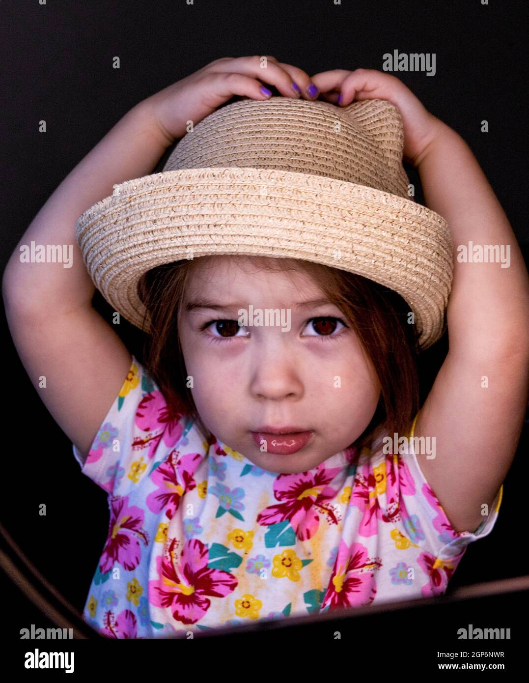 Dolce bambino che tiene sopra al suo cappello di paglia Foto Stock