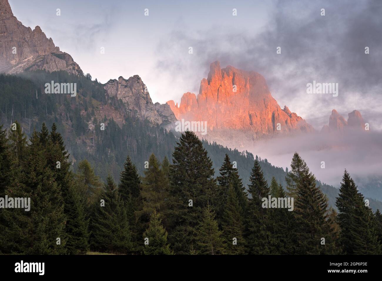 Picco roccioso nelle Dolomiti che brilla alla luce del tramonto in una notte d'autunno nebbia Foto Stock
