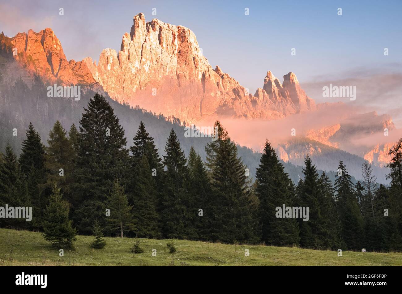 Picco roccioso di montagna parzialmente coperto di nebbia calda illuminata da un tramonto sole in autunno Foto Stock
