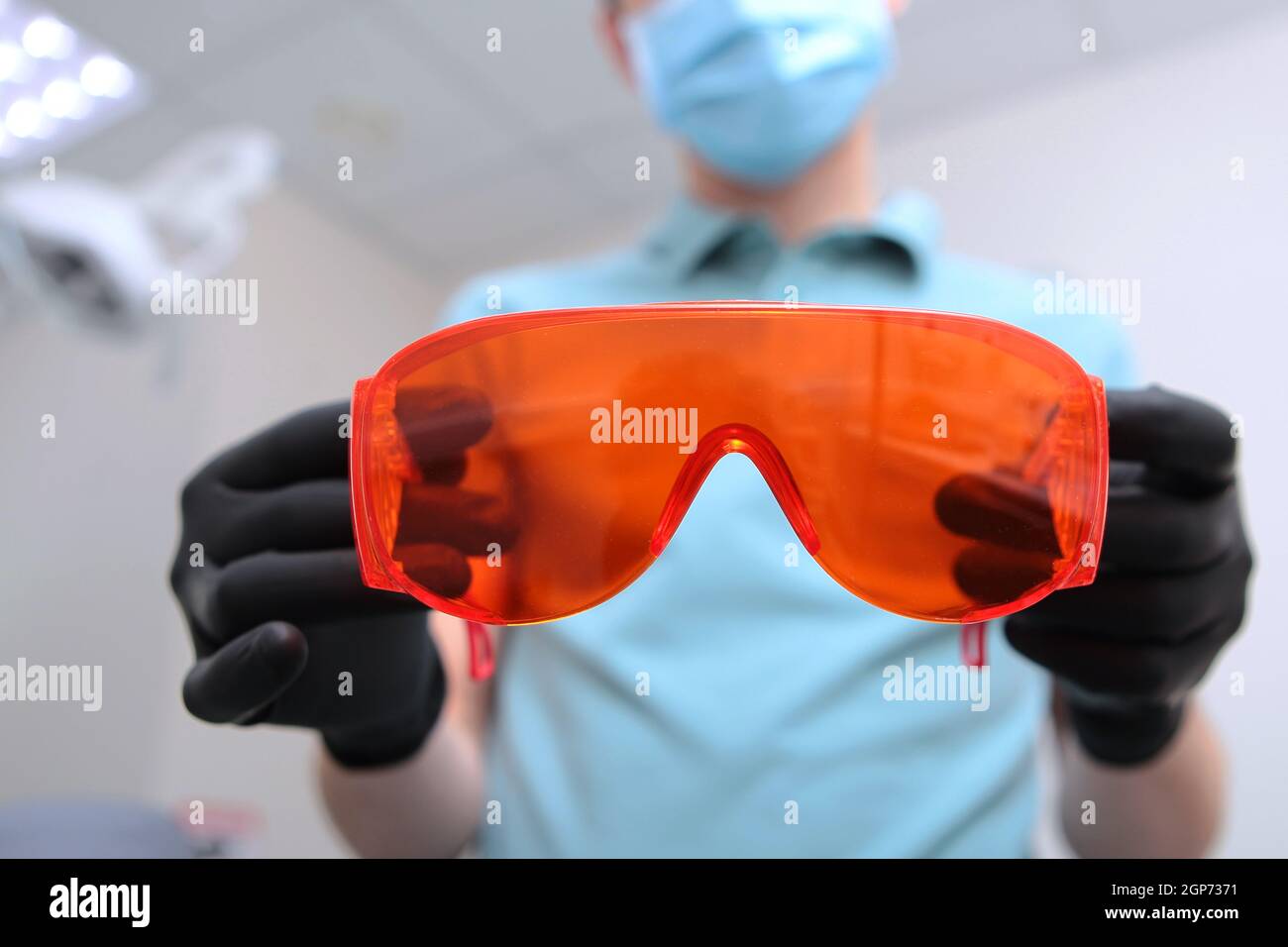 Occhiali di sicurezza arancioni nelle mani di un dentista. Foto irriconoscibile. Spazio di copia. Foto Stock