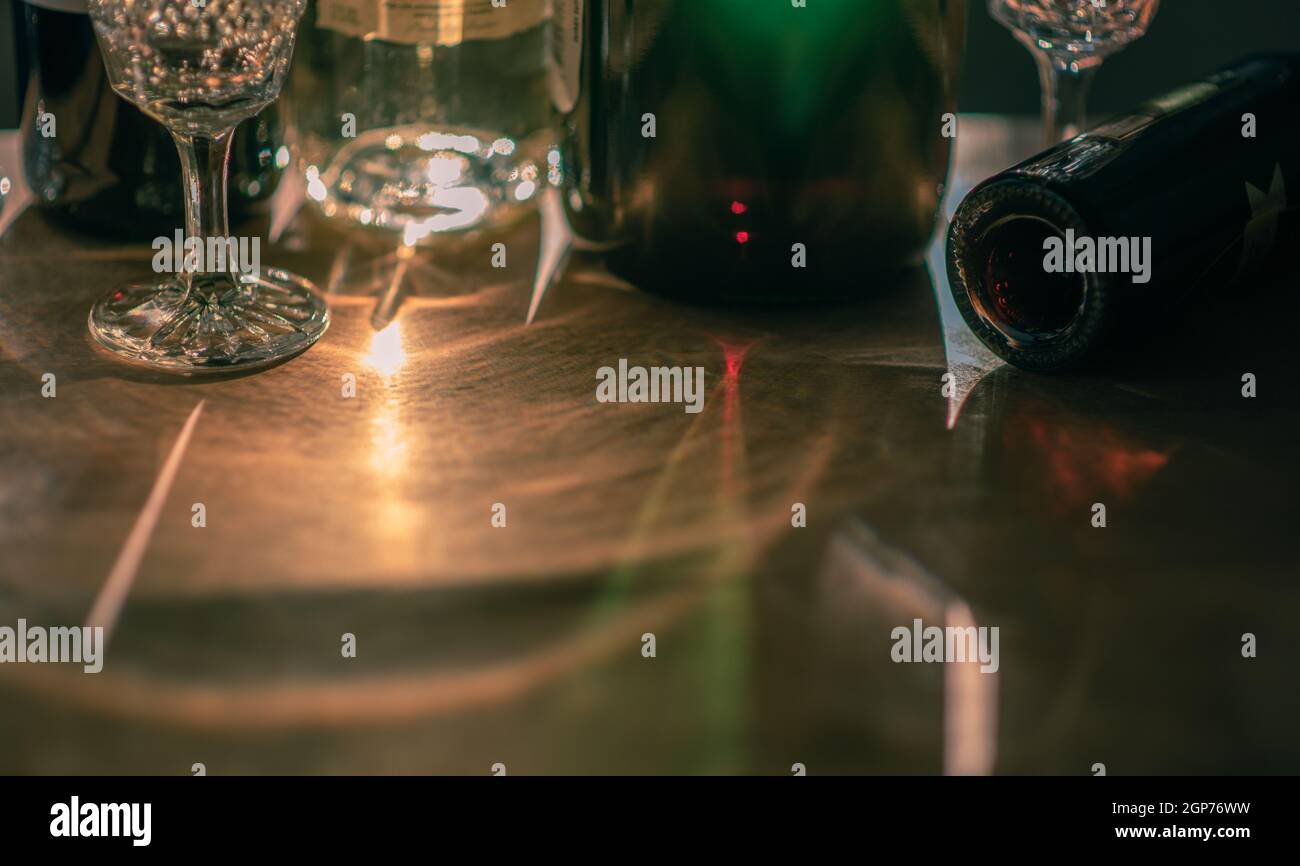Riflessi luminosi da bottiglie e bicchieri di vino diversi su tavola di legno. Spazio di copia. Foto Stock
