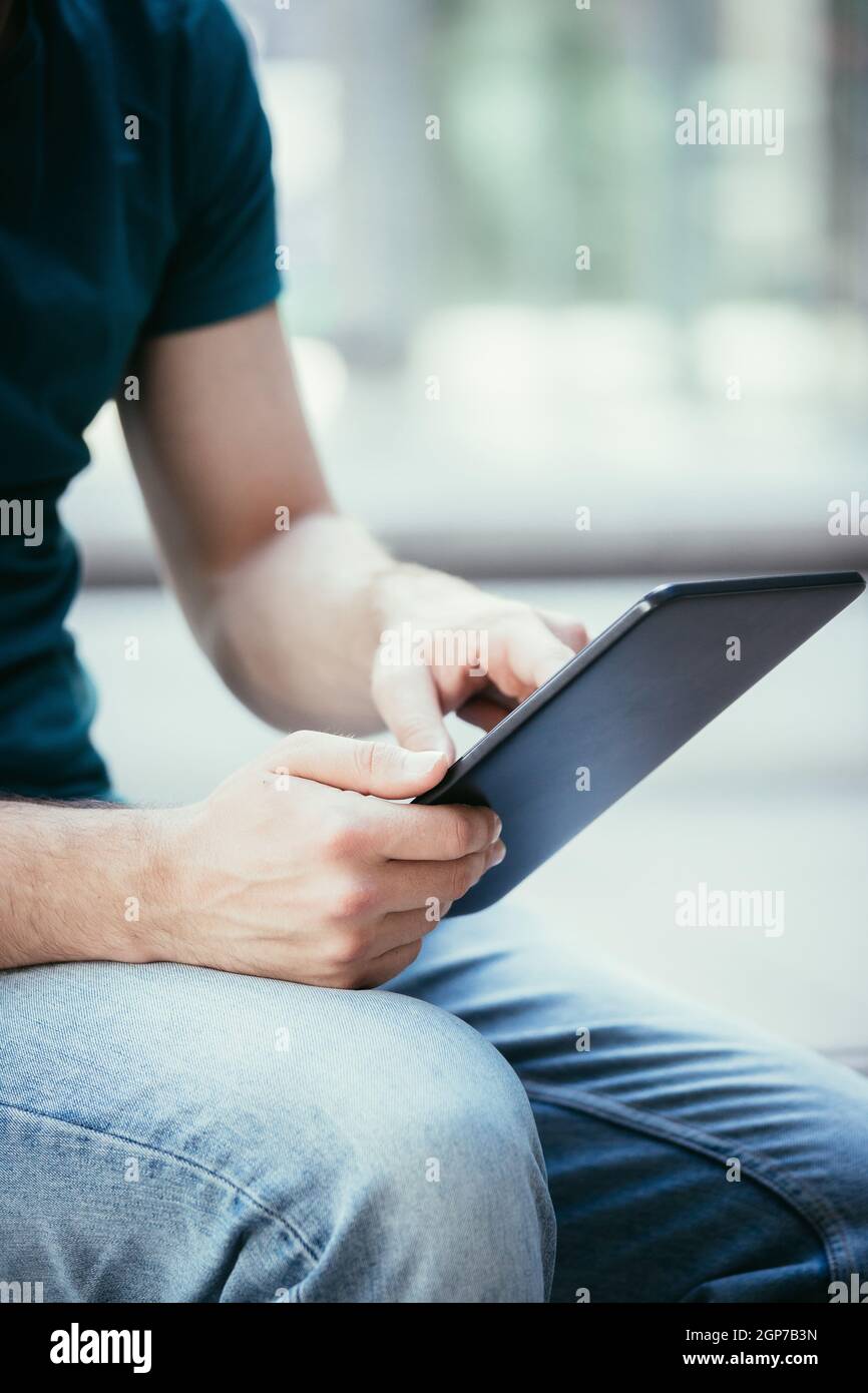 Studente è seduto all'esterno del campus urbano, lavorando con un tablet pc. Close up. Foto Stock