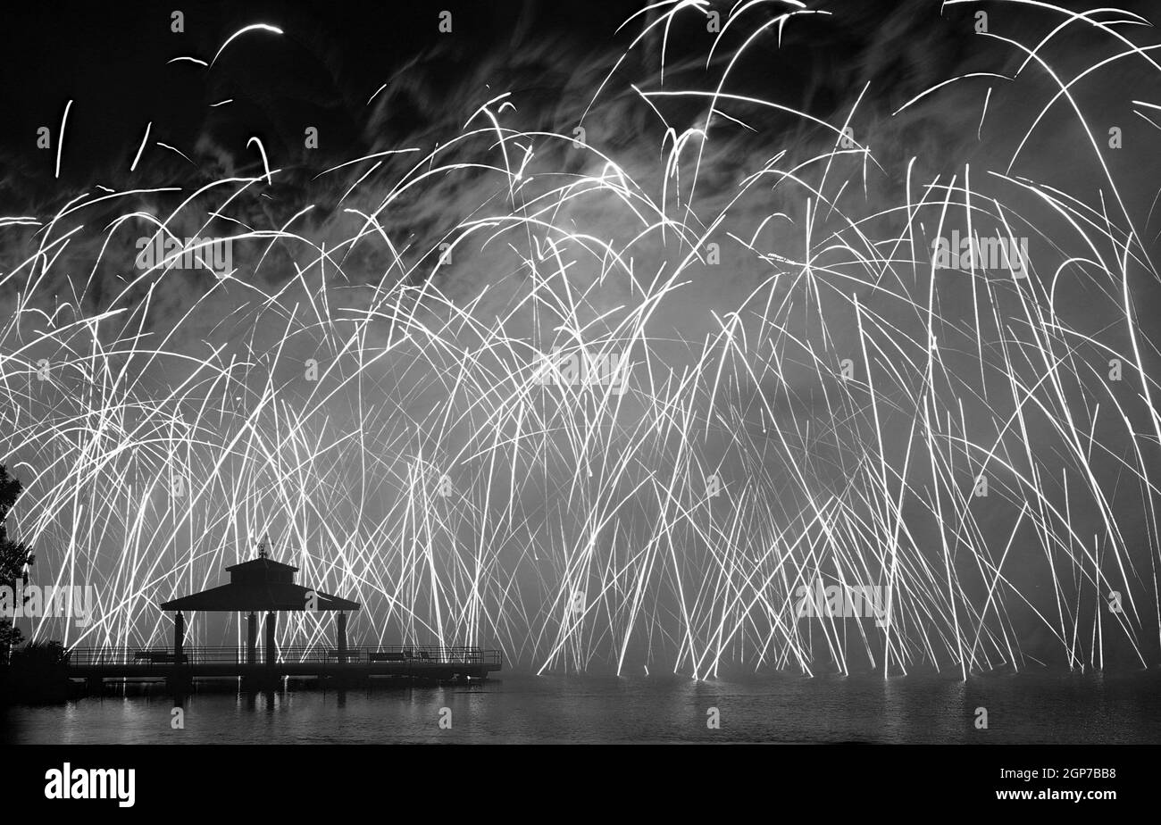 Fuochi d'artificio al Delco Park. Molo di pesca e la silhouette del padiglione in primo piano dei fuochi d'artificio esposti al suolo. Convertito in bianco e nero. Delco Park, Ket Foto Stock