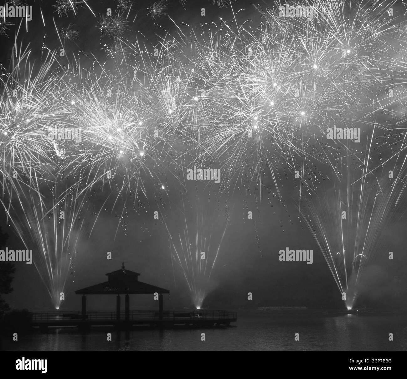Fuochi d'artificio al Delco Park. Molo di pesca e la silhouette del padiglione in primo piano dei fuochi d'artificio esposti al suolo. Convertito in bianco e nero. Delco Park, Ket Foto Stock