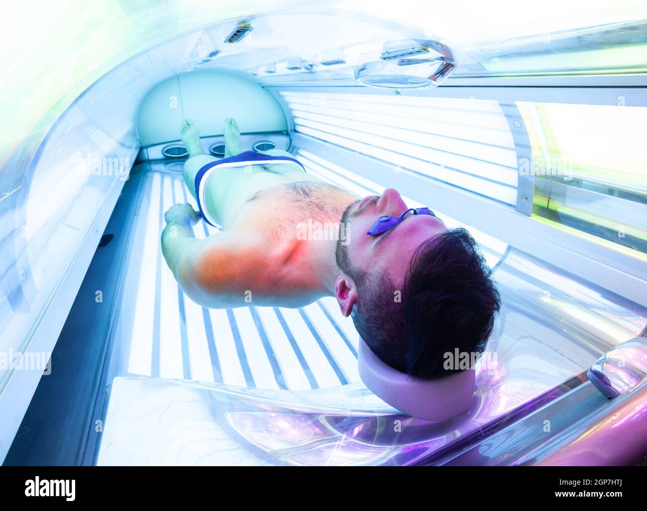 Giovane uomo sottile presso il solarium nel Salone di bellezza. Piena lettino abbronzante. Foto Stock