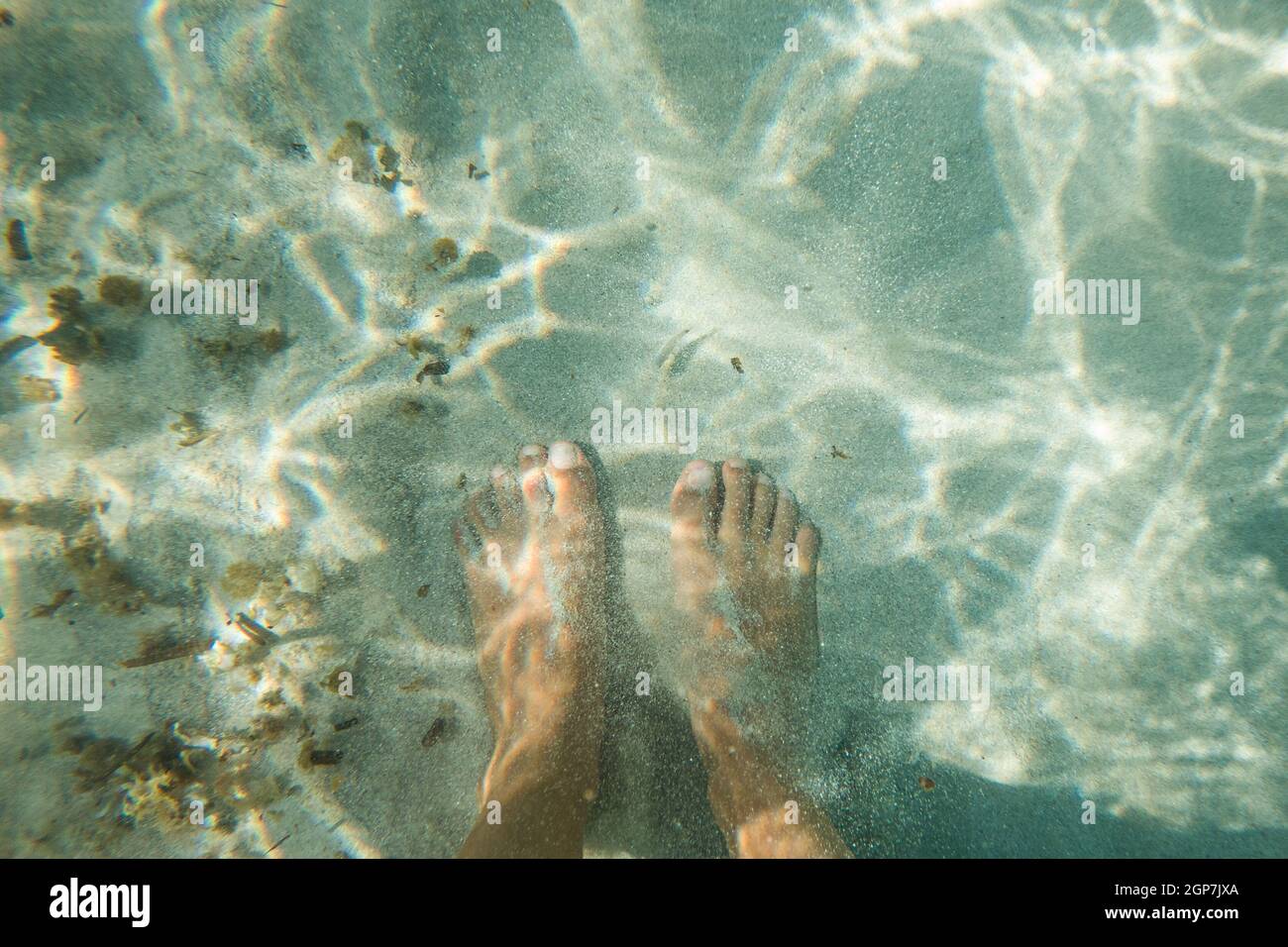 Piedi bianchi che rilassano le dita dei piedi sulla sabbia bianca di una spiaggia Foto Stock