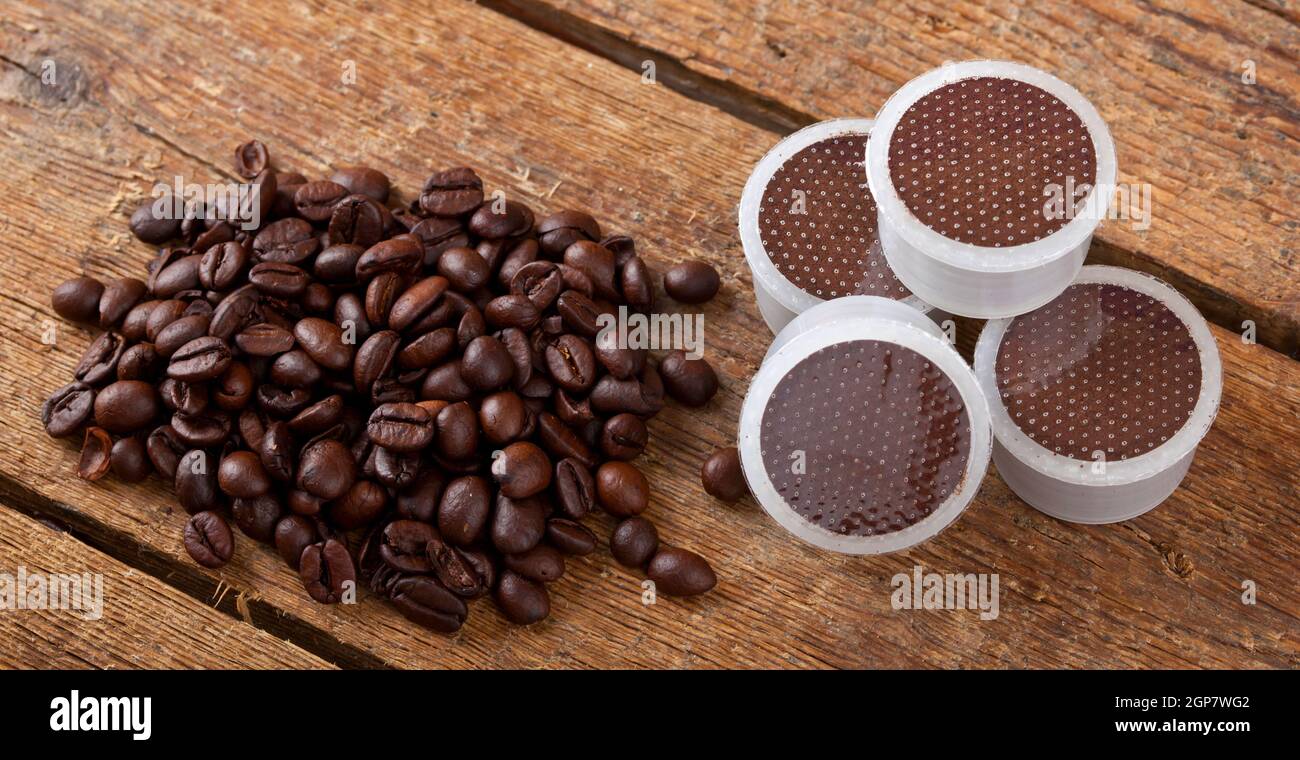 I chicchi di caffè con cialde su un tavolo di legno. Foto Stock