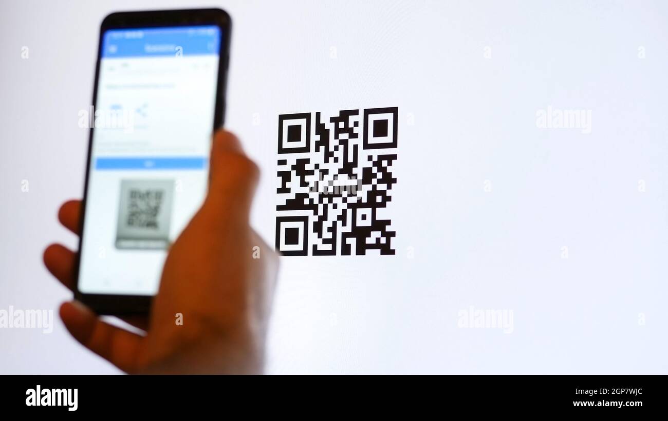 Eseguire la scansione del codice QR con lo smartphone sul monitor del computer. Foto Stock