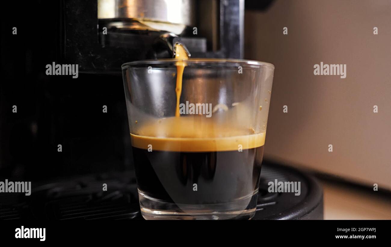 Caffè espresso in una tazza di vetro. Macchina per caffè a cialde. Foto Stock
