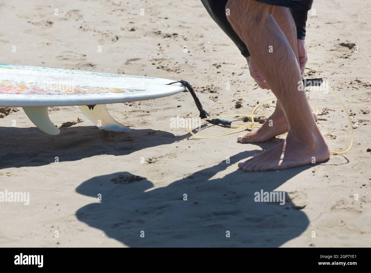 Surfer indossa guinzaglio di sicurezza alla caviglia sulla spiaggia Foto Stock