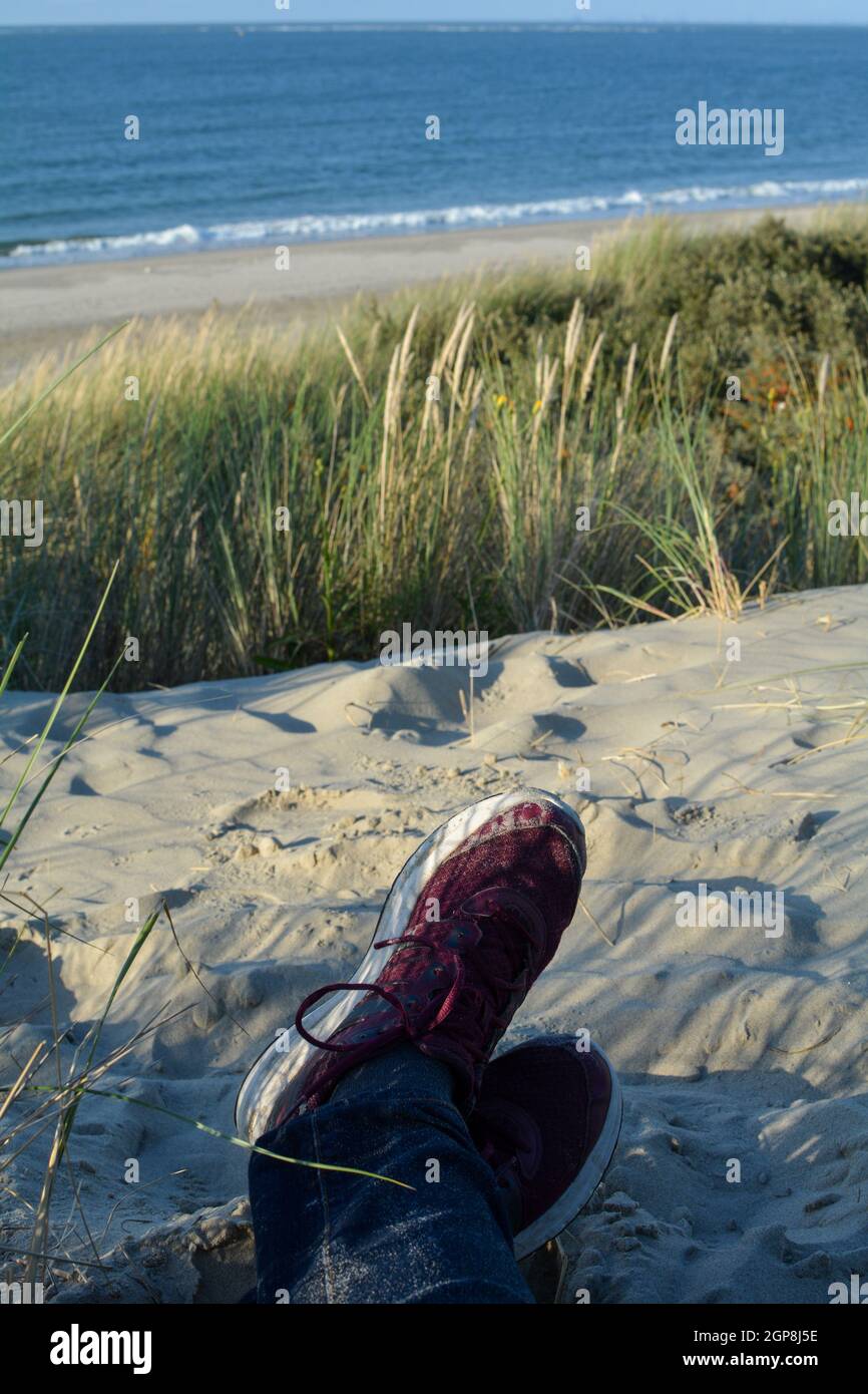 Adagiato tra le dune, adagiato sulla spiaggia con scarpe da ginnastica, con  vista sul mare sulla costa del Mare del Nord nei Paesi Bassi Foto stock -  Alamy
