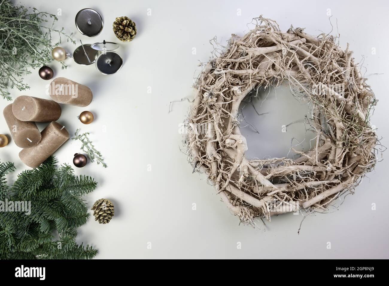 Corona di legno pallido e decorazione come braci fuoco, candele e baubles per le vacanze di Natale e di Avvento su un tavolo bianco, alto angolo di vista da abov Foto Stock