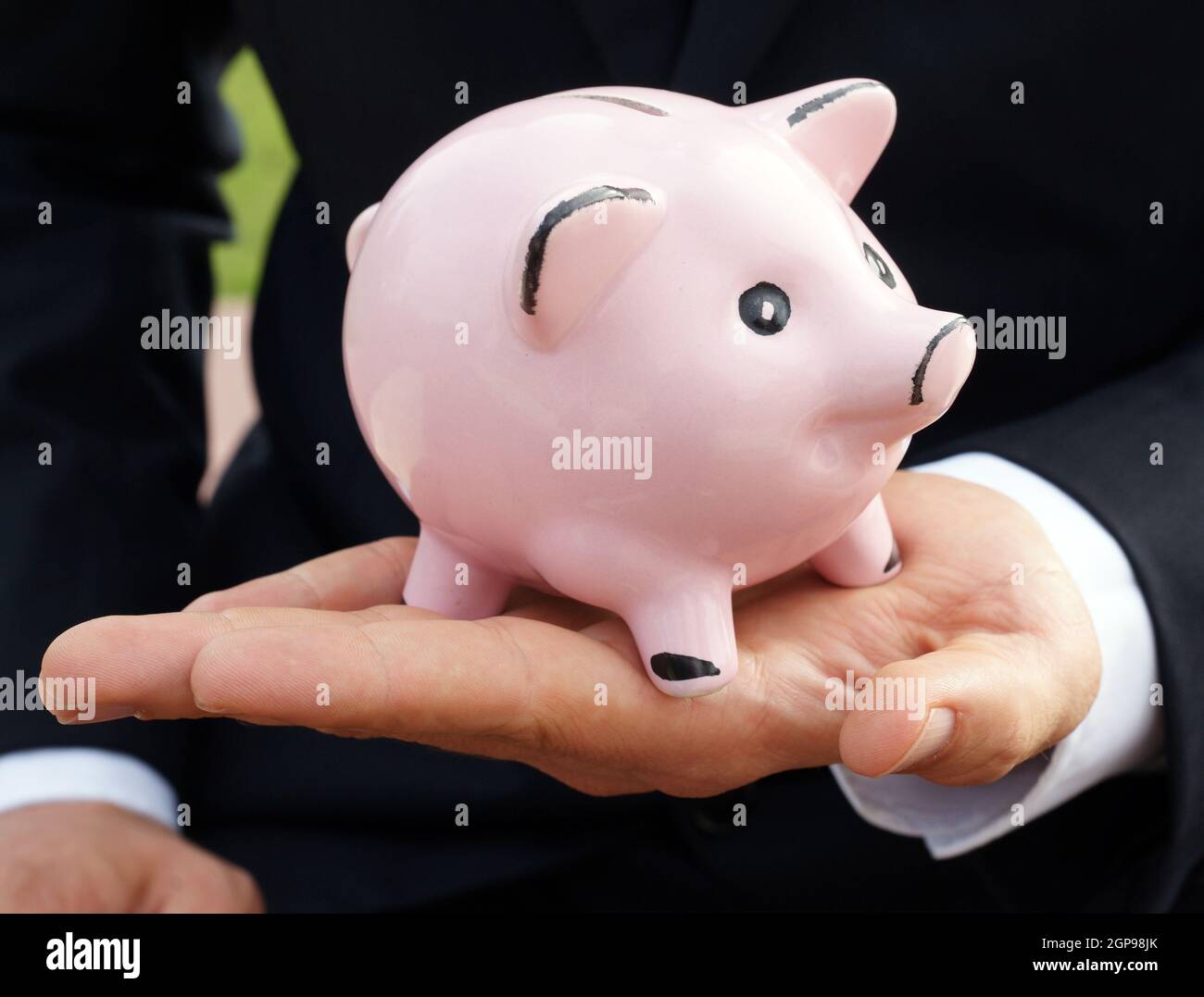 L'uomo d'affari alimenta la banca dei piggy con la banconota tedesca - risparmio di concetto fondi di prestito che investono denaro Foto Stock