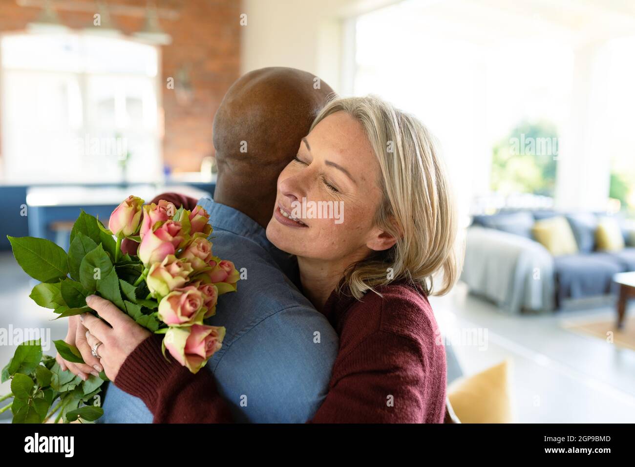 Felice senior diverse coppie in soggiorno abbracciando, tenendo fiori Foto Stock