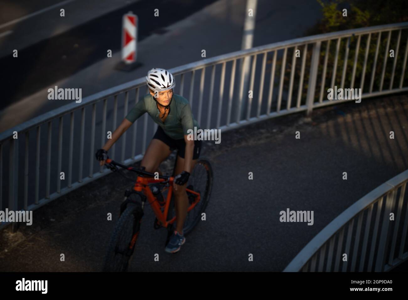 Bella, giovane donna con la sua mountain bike che va per un giro oltre i limiti della città, ottenendo la dose cardio quotidiana Foto Stock