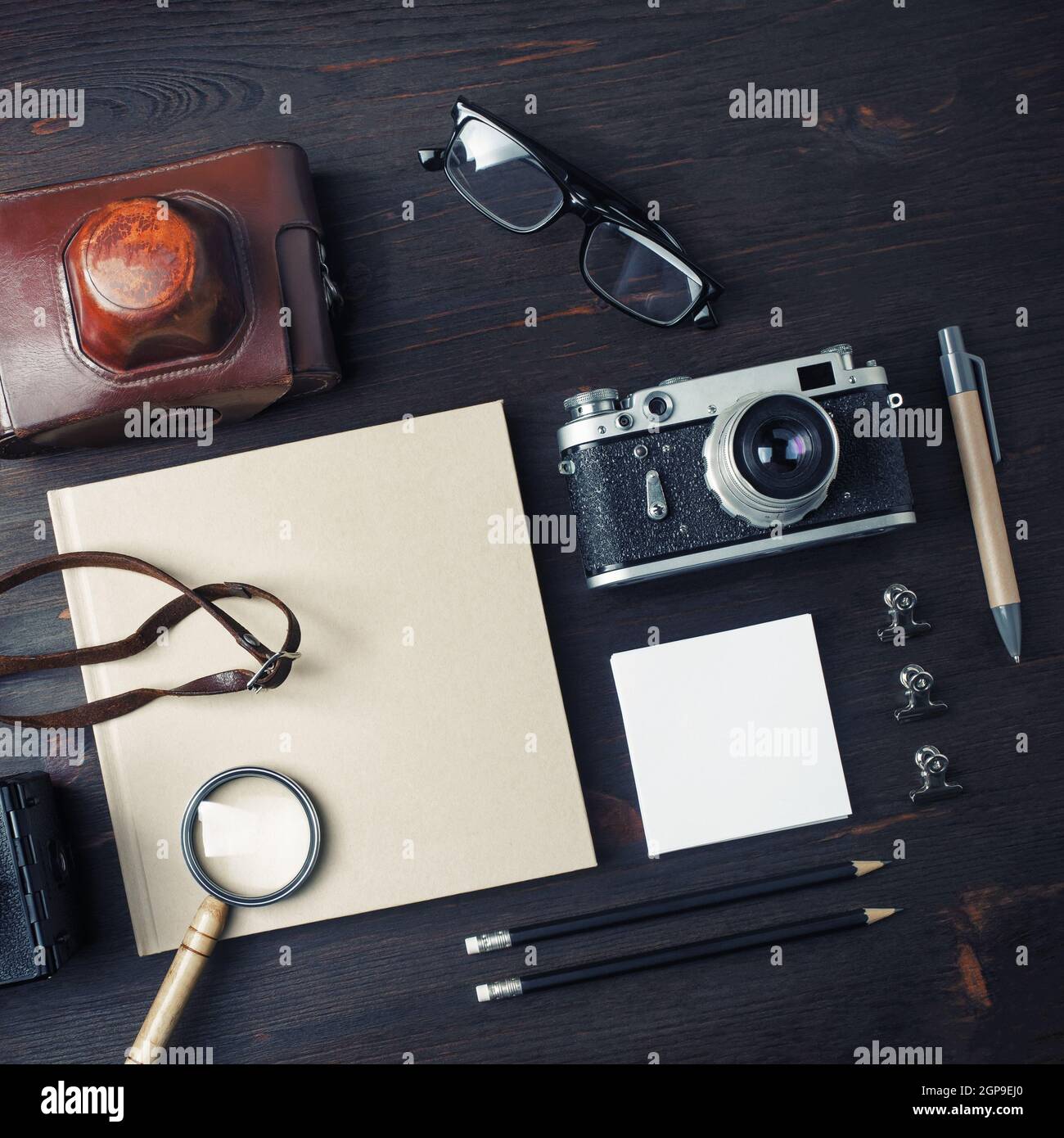Oggetti da viaggio vintage. Cancelleria vuota e fotocamera retrò su sfondo tavolo in legno. Disposizione piatta. Foto Stock