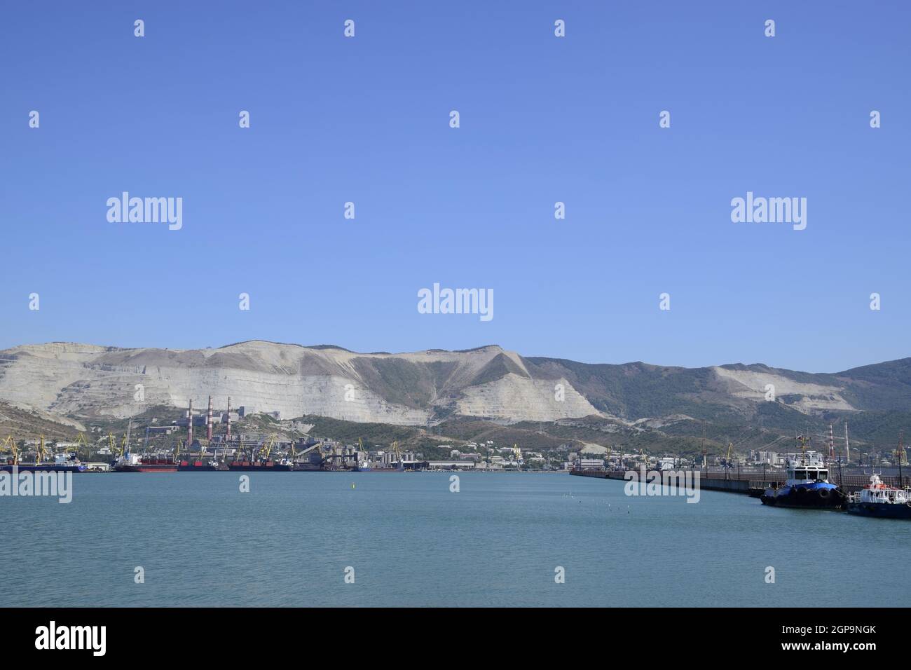 Porti marittimi internazionali. La porta di carico con gru portuali. Baia Mare e costa di montagna. Foto Stock