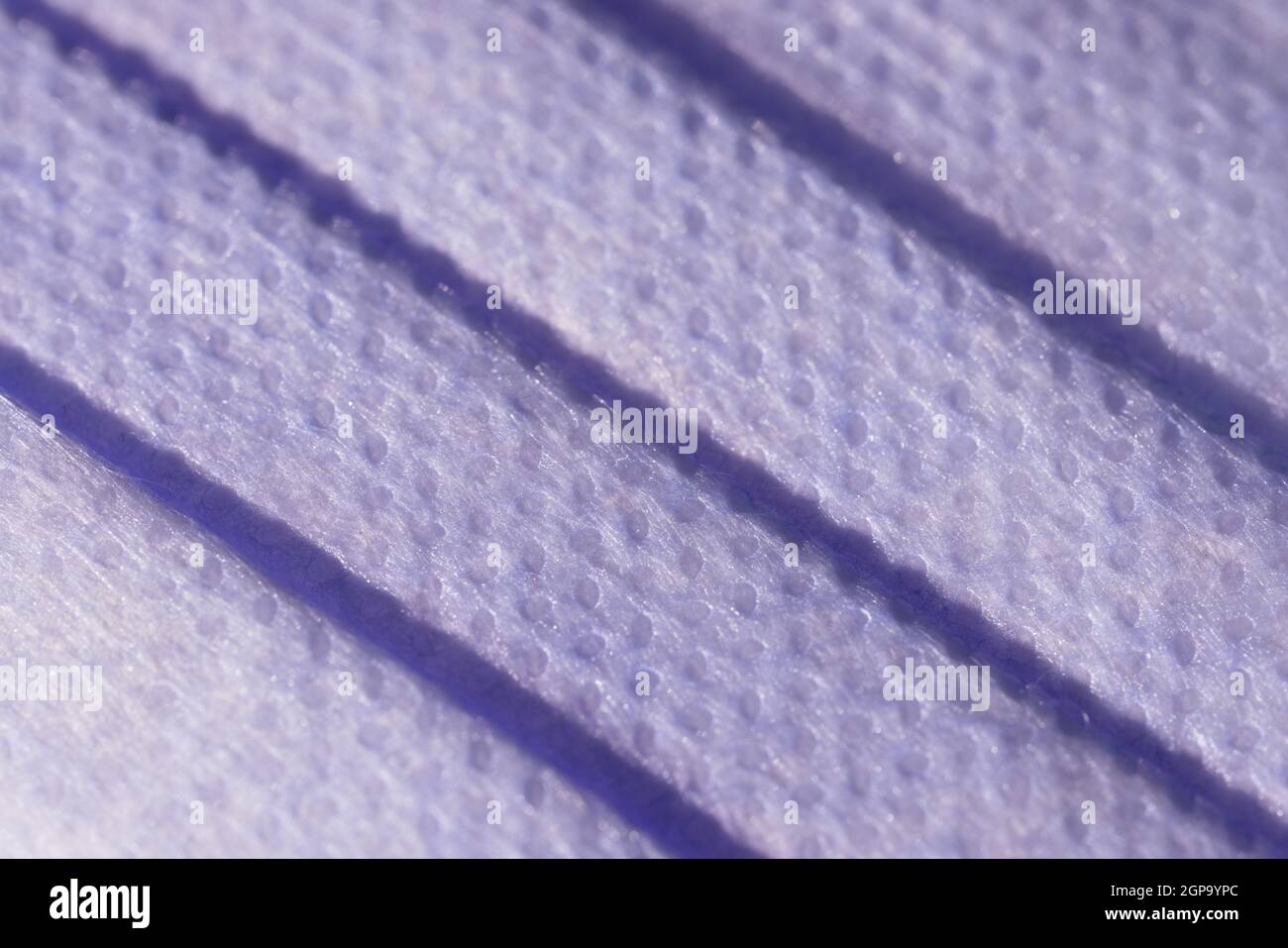 Immagine Super macro che mostra la texture superficiale di una maschera facciale monouso a 3 strati. Maschera medica con 3 pieghe, antispruzzo e capacità filtrante. Foto Stock