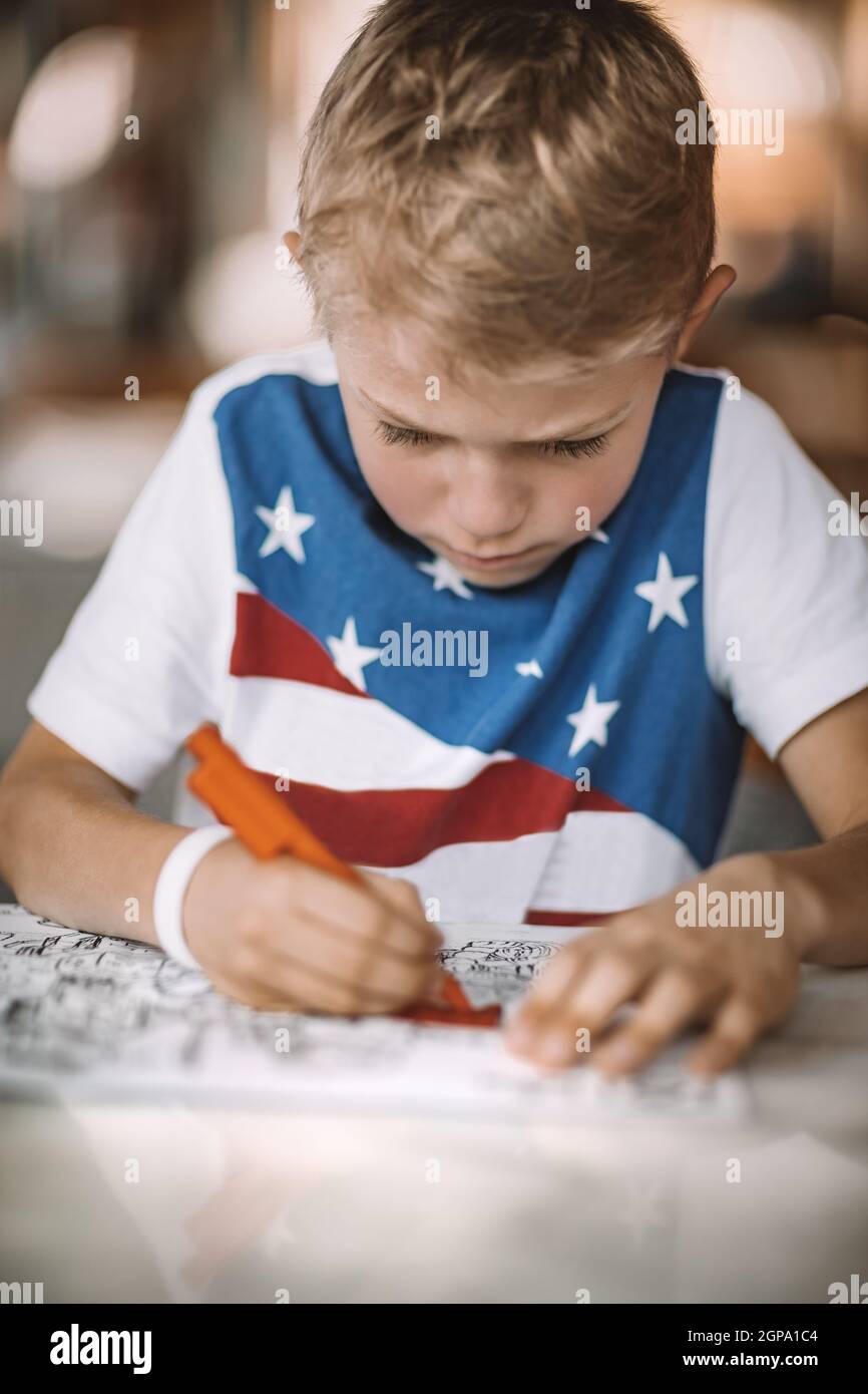 Ritratto di un ragazzo serio con concentrazione disegno e colorazione. Bambini su formazione a distanza. Compiti o tempo libero. Scuola a casa. Foto Stock