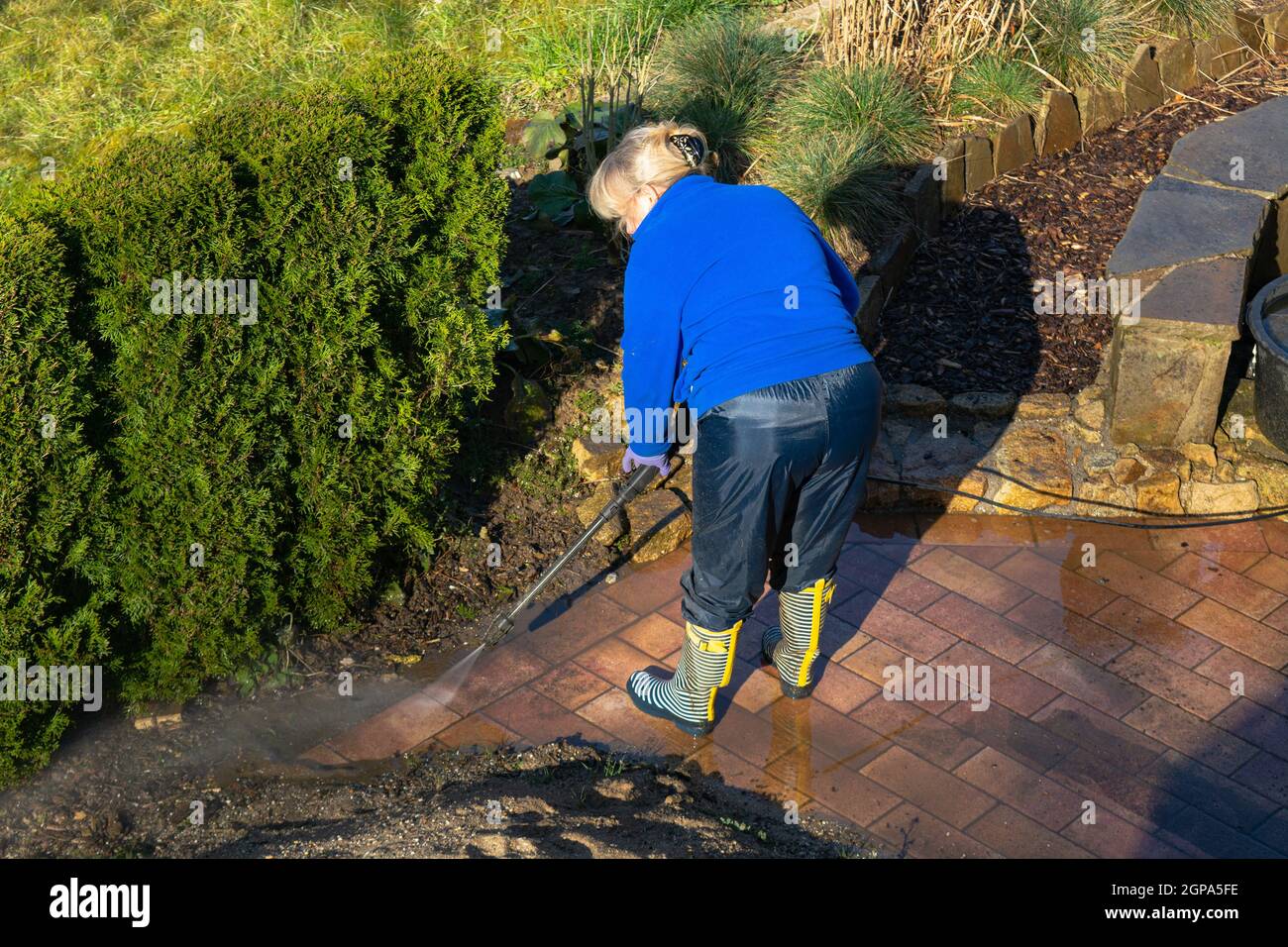 Operaio pulizia vialetto con benzina idropulitrice spruzzi la sporcizia, servizi di pulizia professionale.pulizia ad alta pressione, corpo inferiore. Foto Stock