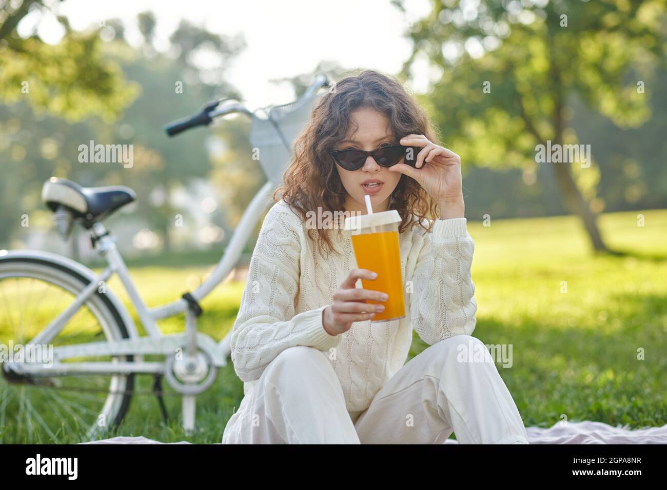 Una ragazza in bianco seduta su un prato nel parco Foto Stock