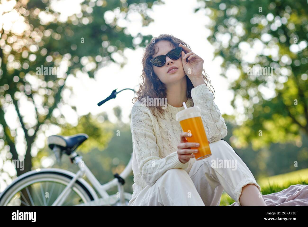 Una ragazza in bianco seduta su un prato nel parco Foto Stock