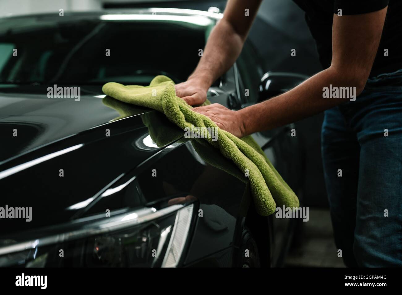 l'uomo pulisce il corpo dell'automobile con un asciugamano. cura di automobile. Foto Stock