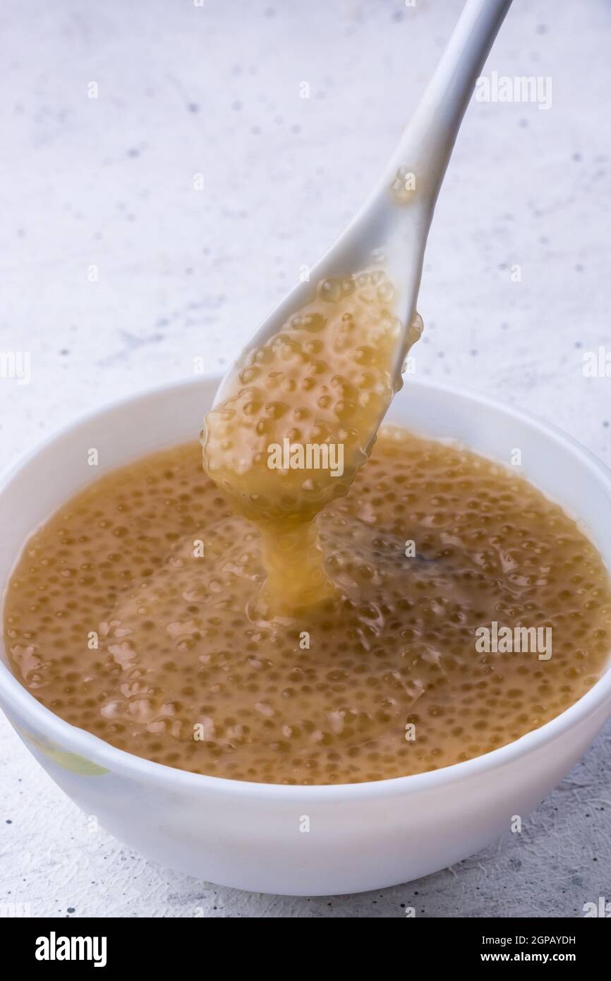 tazza di budino di sago dolce isolato su bianco, fatto con latte di cocco e zucchero di palma o di kithul zucchero, cibo dolce con vista cucchiaio closeup Foto Stock