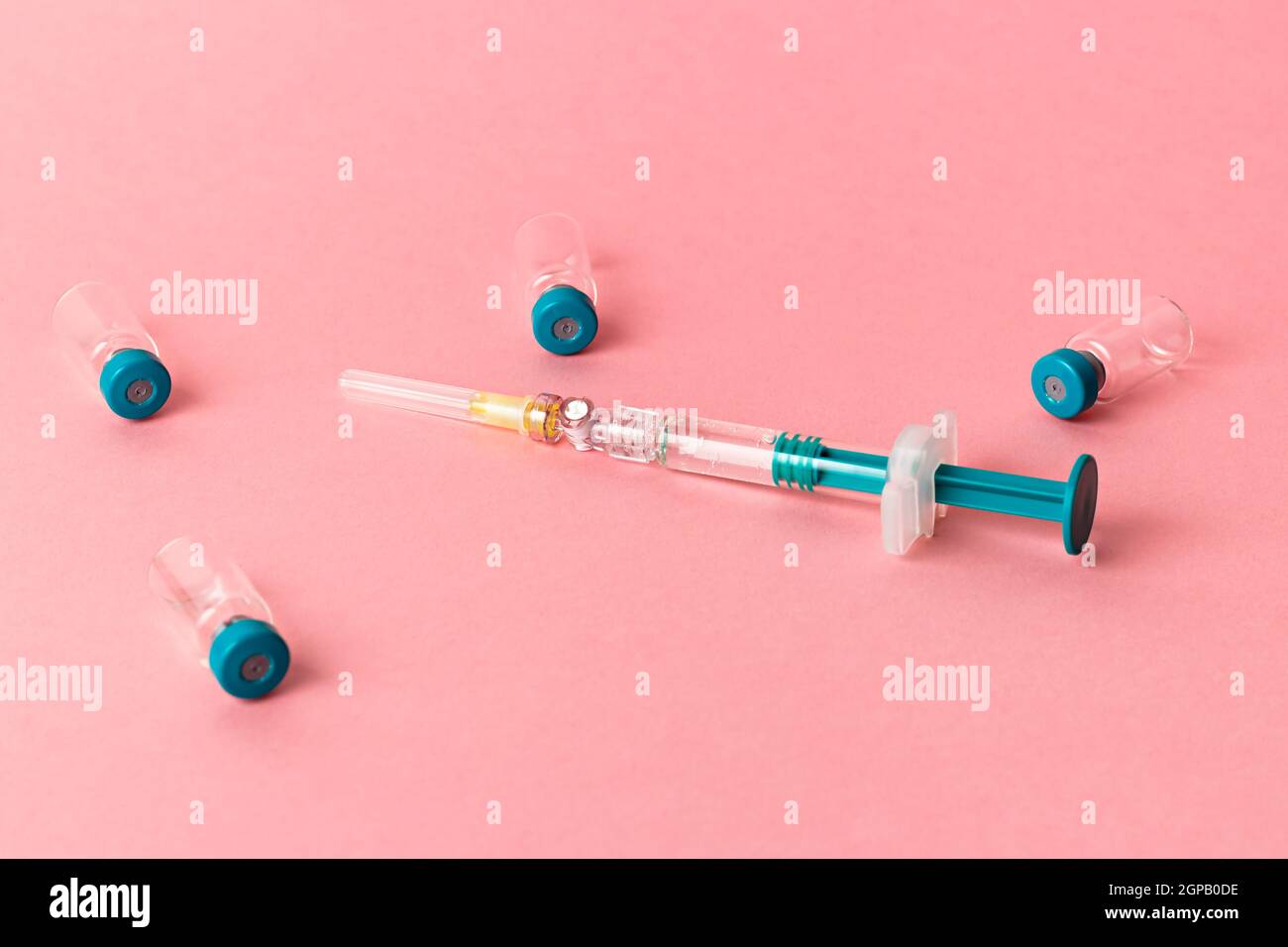 Siringa con diversi flaconcini medici per l'iniezione su sfondo rosa. Foto Stock