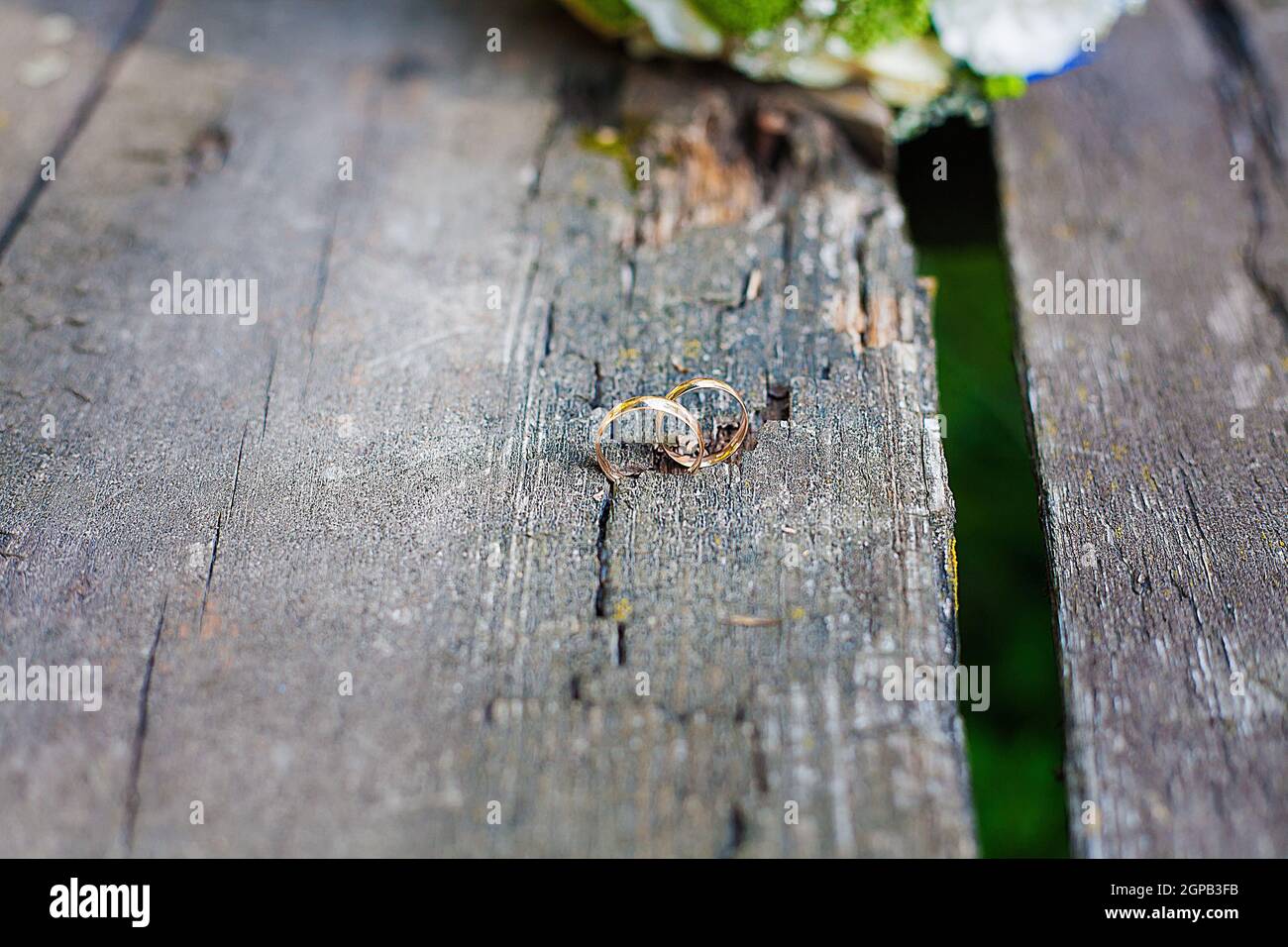 Due anelli di nozze su un pavimento di legno. Foto Stock